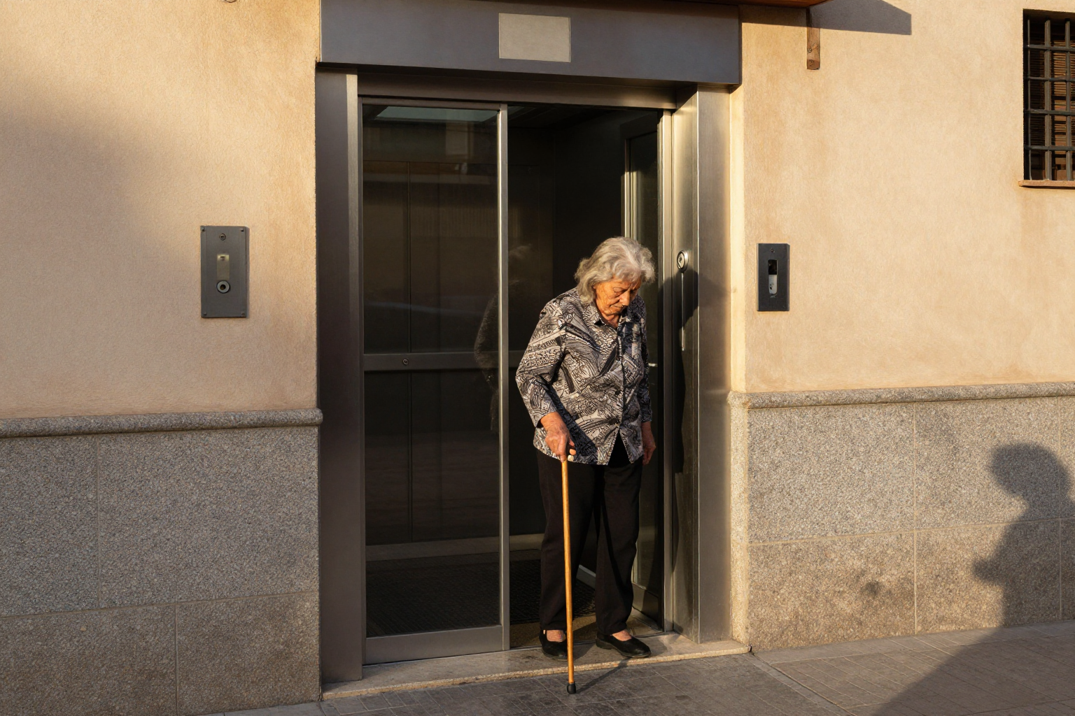 Vecina mayor esperando el ascensor en el portal de su comunidad de propietarios