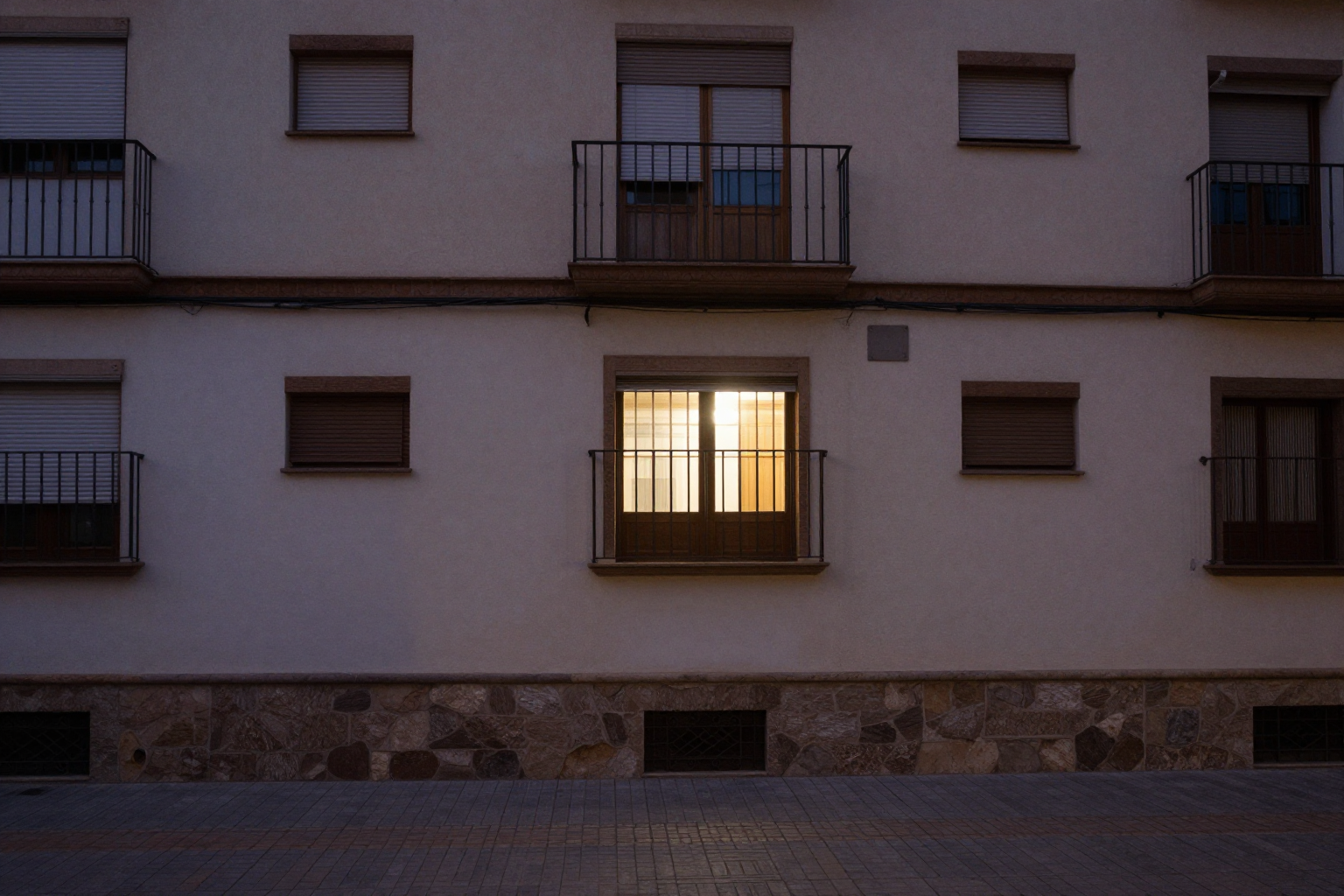 Patio interior de un edificio de viviendas de noche con una ventana iluminada, escenario habitual de los ruidos entre vecinos